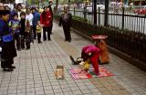 Girl balancing on mouth getting ready to spin while the girl in the background spins a plate. Jishou City, China.
