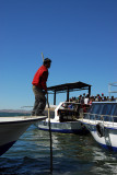 Crew member poling the boat alongside the pier