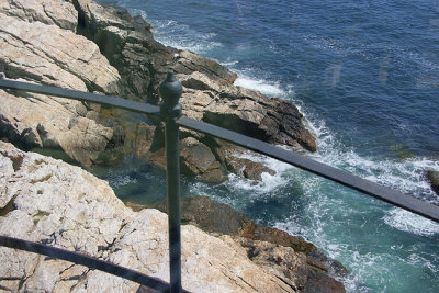Lighthouse view of railing and rocks.