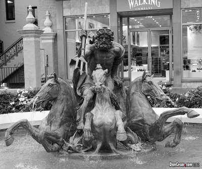 Neptune, god of the sea, raises his trident and roars through turbulent waters led by three powerful horses.