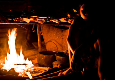 Lujan by the fire. Fire is everything here. Beside cooking, it keep the hut warm, light the place up, keep the mozzies away.