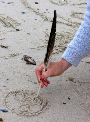 Feather, hand and sand