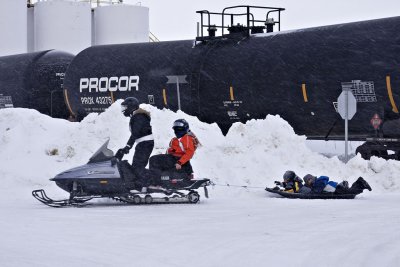 Snowmobile passing oil tank cars