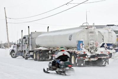 Snowmobile passing oil trucks