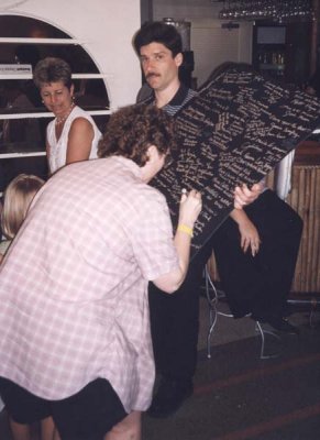 Susan signs poster as Donald holds