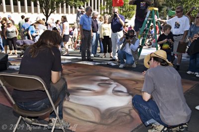 Local man, kneeling in shadows, shoots artist as she discusses her work.   Arraignment next Friday.