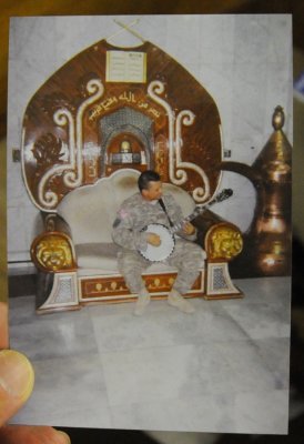 Photo of Chad pickin his banjo while sitting in one of Saddam Hussein's thrones.