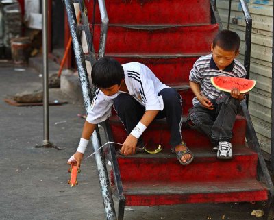 Tibetan boys play with their watermelon car and boat.
