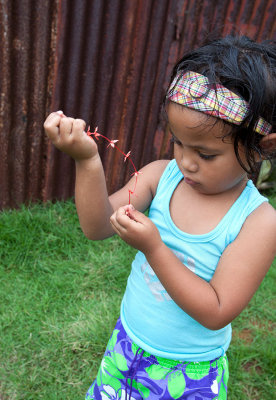 3 1/2 year old girl strings together flowers for a necklace. Pohnpei, FSM IMG_7604.jpg
