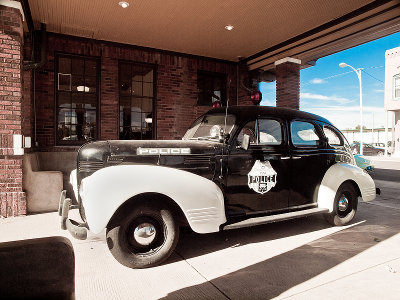 An old timey police car parked at the end of the depot