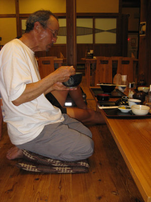 Jay doing a yoga knee stretch while eating dinner.
