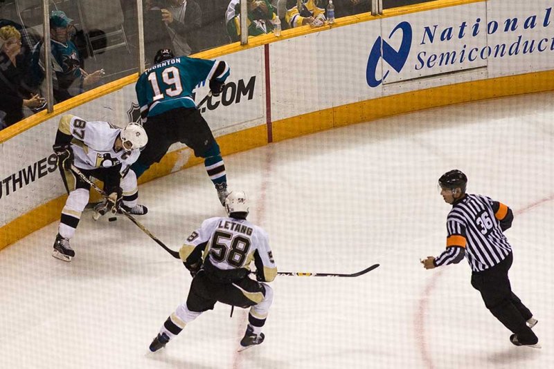 Sidney Crosby and Joe Thornton fight for the puck