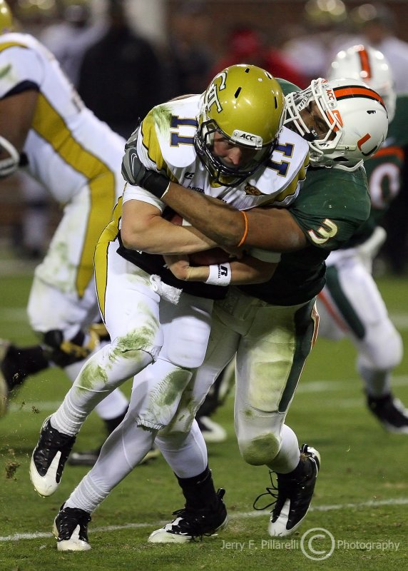 Jackets QB Shaw covers up as he is tackled by Canes LB Cook