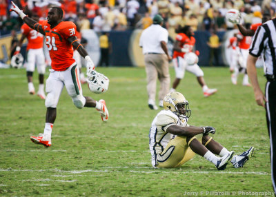 Jackets LB Brandon Watts sits dejected on the field as Miami players celebrate their overtime victory