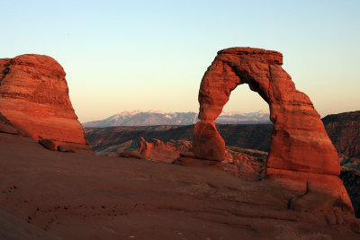 The last bit of sunlight bathes Delicate Arch and the La Sal Mountains in the distance