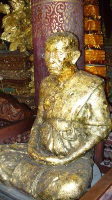 Thai people venerate wise monks, in addition to the Buddha.  They buy small squares of gold leaf and decorate the statues.