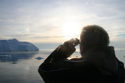 Tourist taking a picture of the midnight sun over the icefjord