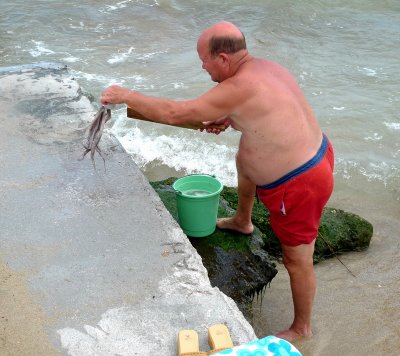 This fisherman is slamming the octopus 
on the rock to make it soft ... 
Then eat raw