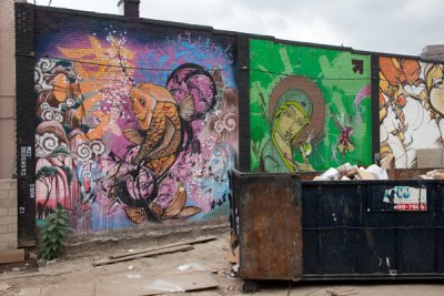 Three Murals Behind Trash