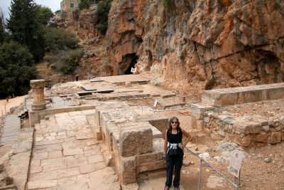 Banias: Judy on the ruins of the Goat Temple. Behind her: Nemesis Courtyard, Temples of Zeus & Pan, and the cave.
