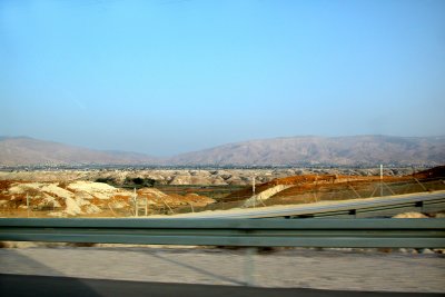 Driving through the West Bank: Fence separates Jordan from the West Bank. Jordanian village & mountains are in background.