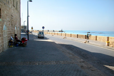 Man selling pomegranate juice - near the Mediterranean Sea in Jaffa. Fisherman & entrance to old Jaffa port in the background.
