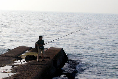 A fisherman on a jetty - the beach in Tel Aviv on the Mediterranean Sea.