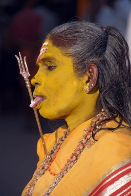 Woman covered in Yellow Paste with Trident through her Tongue