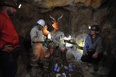 Tour guide explaining how the miners make offerings of coca leaves and alcohol to El Tio.