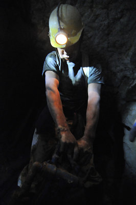 A drunk miner dragging his air hammer out of the mine after a long days work.
