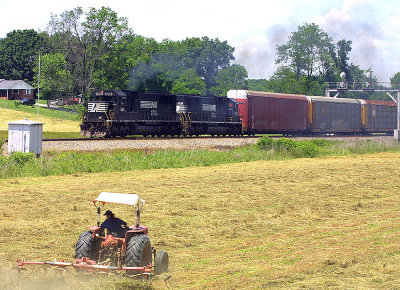A farmer works a hay tether over the field at Bowen Ky as NS 223 passes by