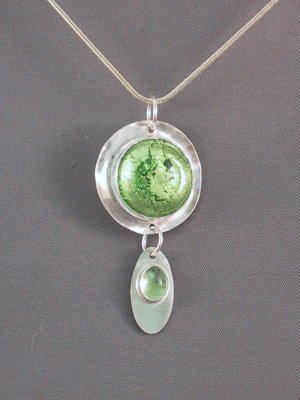 This green Murano glass pendant is accented by a 5x7mm peridot dangle.  The glass is 20mm in diameter, and the entire pendant is 53mm from top to bottom.  Murano glass purchased in Murano, Italy. Sold