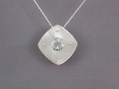 This 27 mm square rivetted pendant features a 12mm rhinestone in the centre. It can be worn as shown, or hanging square to the chain.Sold