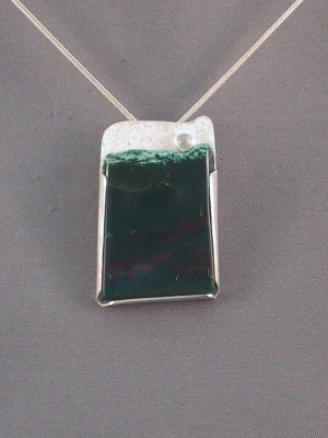 'Moon over the ocean'This pendant features a 27 x 30 mm bloodstone with a 4 mm moonstone.  The bloodstone is held to the pendant by tabs cut out with the backplate.