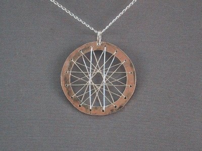 This spirograph pendant has fine silver wire criss-crossing the centre.  35mm diameter.