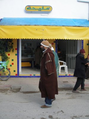 Pedestrians walk by colorful shop, Testour