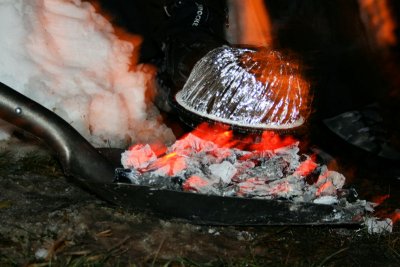 Jiffy Pop popped over coals in a shovel