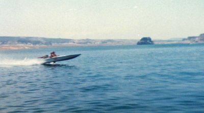  High School Classmates Rod And Jeff moved to Page Az. and Lake Powell shortly after high school. Jeff bought this flat bottom boat with a Ford 427 motor and show here  Testing It Out  a bit. Soon , he had my other buddy Rod up sking behind it at,,,say 80 mph!!! Amazingly, both this friends are still alive today and this bad scan of an even worse, blurry Kodak 110 photo is all I have and a few memories of that wild 1980 vacation. ( NOte: LOne rock is in the background near Wahweap Marina. In the early daysm there was little law inforcement down at Lone Rock and someone would need to be almost dead before anyone would ever show up. Today , is a different story and tickets are handed out like  Gum Sticks  for any infraction of any set rules.. New Days verse Old ??????? Chalk up one for the  OLd Days ,,,,