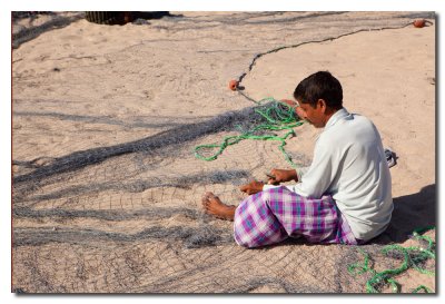 Pescador reparando una red en el puerto - Fisherman repairing a fishing net in the port