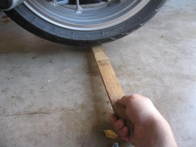 Lift up on board to lift rear wheel so you can remove pressure from the bolts to remove them