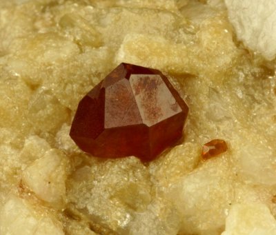 An icositetrahedron (with small dodecahedron face) of spessartine, 7 mm on 5 cm matrix, Gilgit, Pakistan
