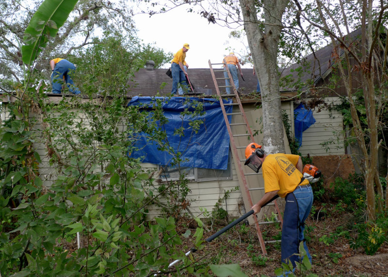 PART OF THE TEAM WORKED ON THE TEMPORARY ROOF TARP AND THE OTHERS CUT UP DOWNED TREES AND BRUSH