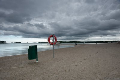 A life bouoy and a trash bin on a cloudy beach