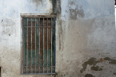 Worn out green window with bars