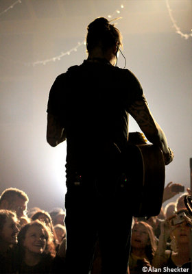 Michael Franti - silhouetted as he performs a song from a platform out by the soundboard