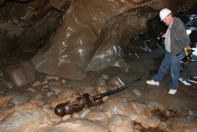 Tom examining metal shaft on floor of sea cave