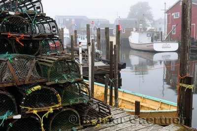 Wood lobster traps on dock and boats in fog at Fishermans Cove Eastern Passage Halifax Nova Scotia