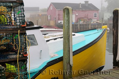 Lobster traps with yellow boat and red house in fog at Fishermans Cove Eastern Passage Halifax Nova Scotia