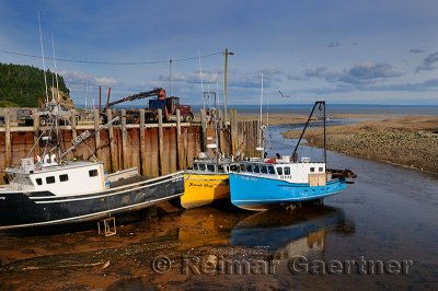 Boats moored at the Alma wharf at sundown low tide on the Bay of Fundy New Brunswick