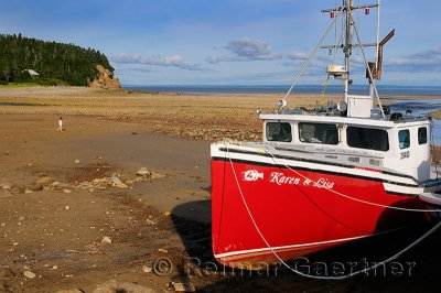 Young girl walking on Ocean floor next to an achored boat on the Bay of Fundy Alma New Brunswick